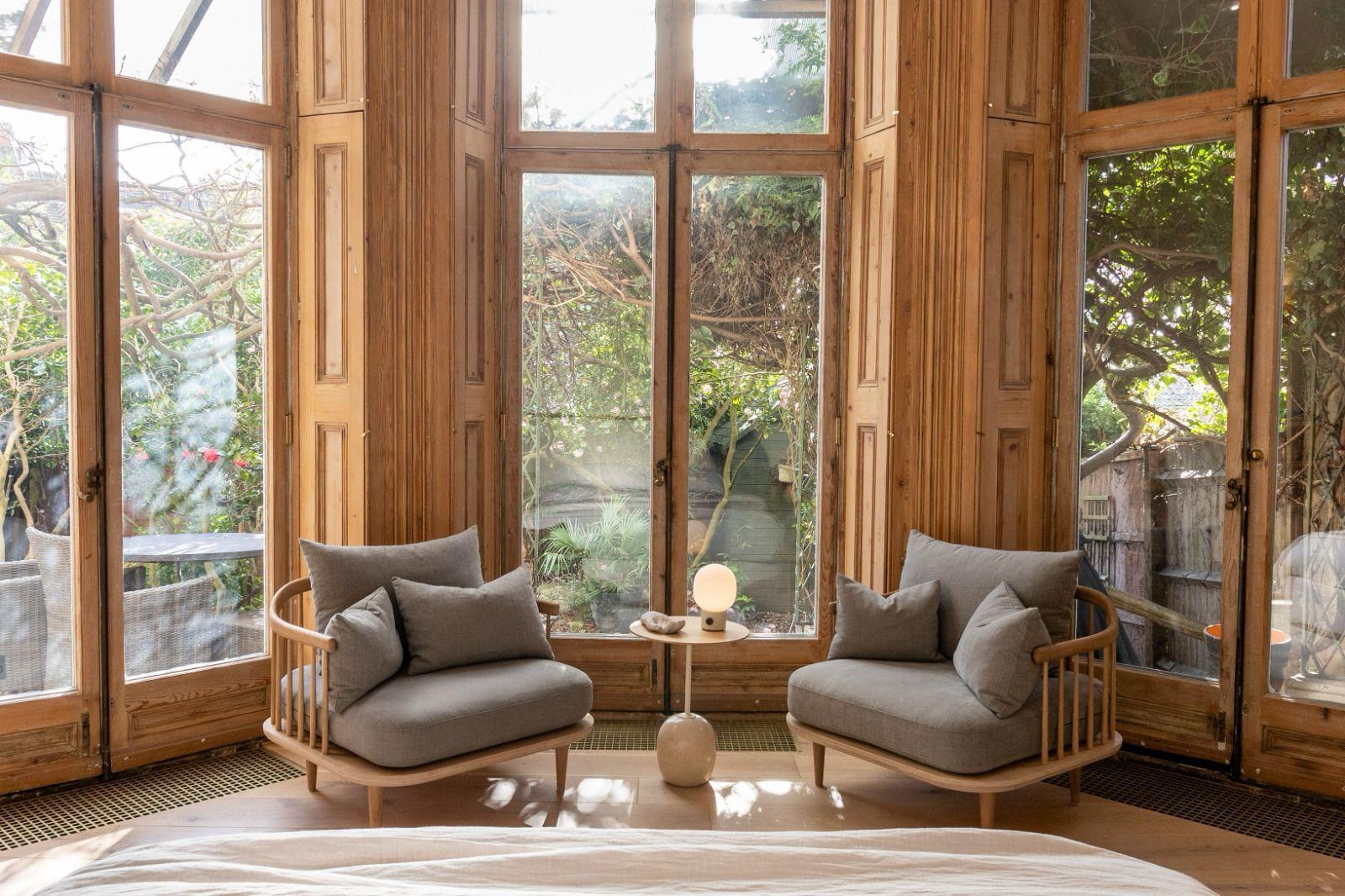 Chairs in bedroom with timber pillars and a garden out the windows